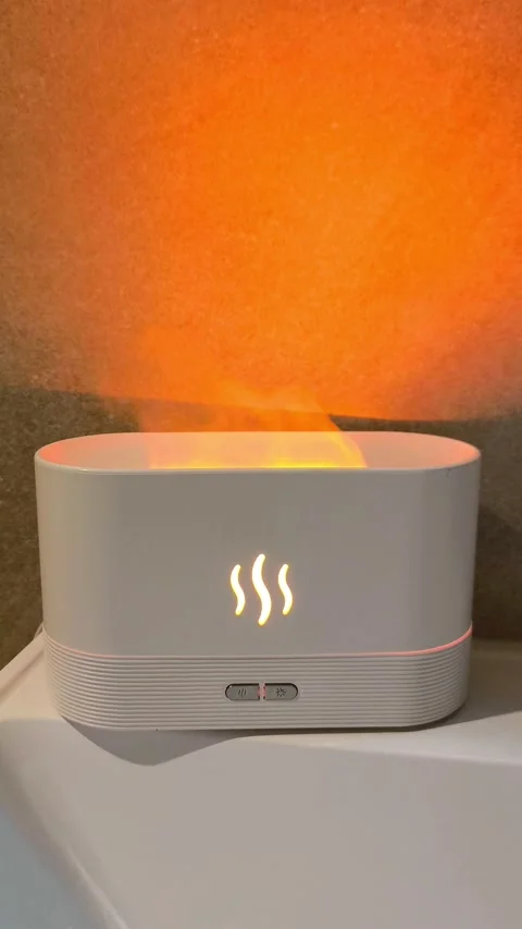 White aroma diffuser, air humidifier with flame effect, steam against warm Stock Footage 320373977