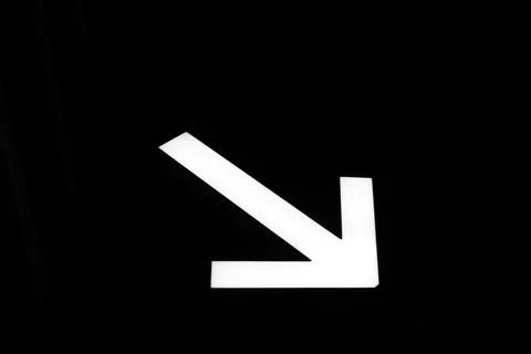 White arrow to the lower right corner on a black background Stock Photos