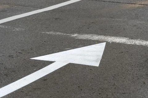 White Arrow Marking on Pavement Indicating Direction in a Parking Area Duri.. Stock Photos