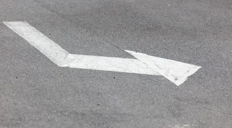 A white arrow pointing down on a grey road Stock Photos