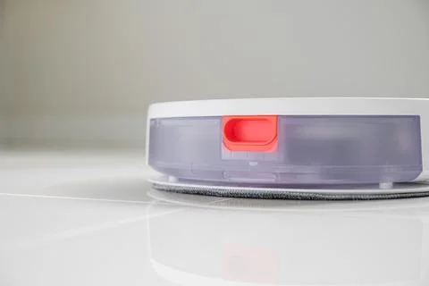 White automatic floor cleaner with side brush on tile flooring. Back view s.. Stock Photos