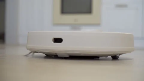 White automatic vacuum cleaner cleans the floor from debris Stock Footage 219811412