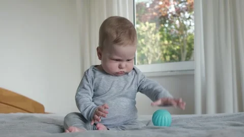 White baby exploring blue toy on bed Stock Footage 336076498