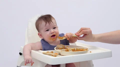 White background. An adorable baby eats independently from a plate Video stock 332265245