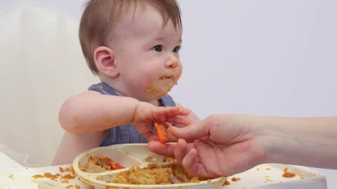 White background. An adorable baby eats independently from a plate Video stock 332267098