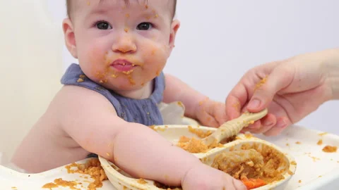 White background. An adorable baby eats independently from a plate Video stock 332267647