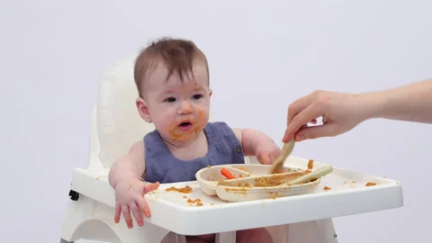 White background. An adorable baby eats independently from a plate Video stock 332268869