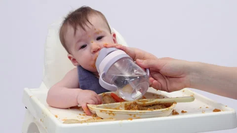White background. An adorable baby eats independently from a plate Video stock 332270923