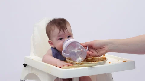 White background. An adorable baby eats independently from a plate Video stock 332270954