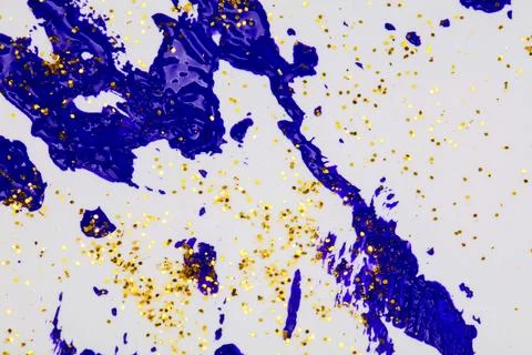 On a white background, blue splashes of acrylic paint with gold sparkles. Stock Photos