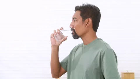 White background, healthy middle-aged Asian man drinking a glass of water a.. Stock Footage 255385719