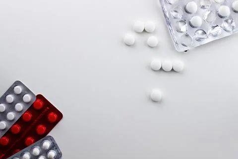 On a white background on the left are three blisters with pills, on the top r Stock Photos