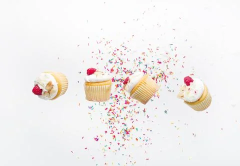 On a white background with multi-colored confetti, small muffins with cream a Stockfoto's
