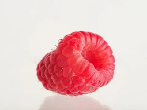 On a white background one raspberry. Appetizing red berry. Lots of minerals a Foto stock