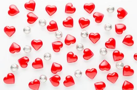 White background with red hearts pattern and silver baubles, flat lay Stock Photos