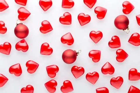 White background with red hearts pattern and red baubles, flat lay Stock Photos
