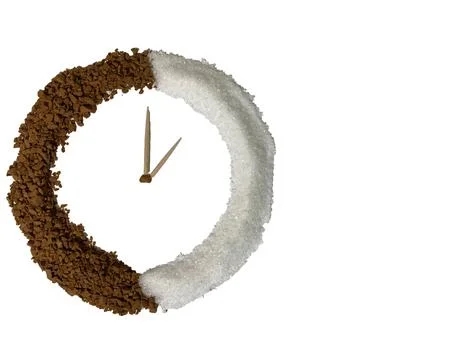 On a white background is a round clock made of coffee and sugar. Stock Photos
