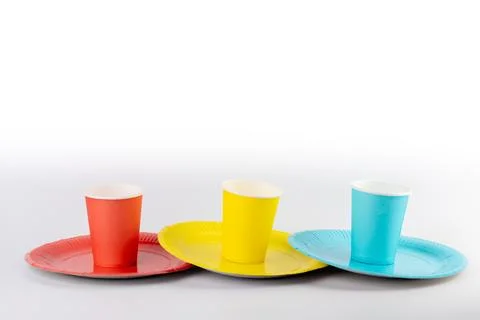 On white background there are three paper cups yellow red and blue with matching Stock Photos