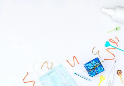 White background with wrapped giftbox, streamers, candles, medical face mask, Stock Photos
