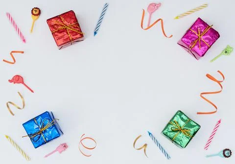 White background with wrapped giftboxes, streamers, candles and skewers. Birt Stock Photos