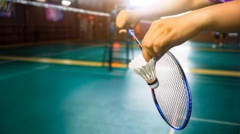 White badminton shuttlecocks being served by hands in indoor badminton cour.. Stock Photos
