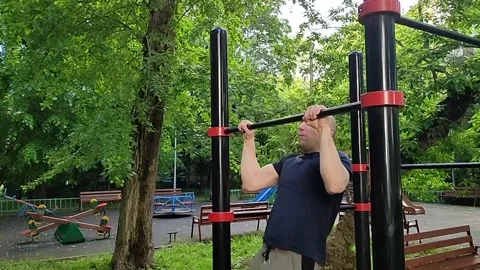 A white, bald man pulls himself up on the crossbar Stock Footage 197356764