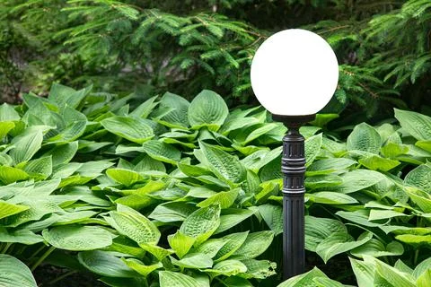 A white ball lantern on an iron pole of ground lighting. Stock Photos