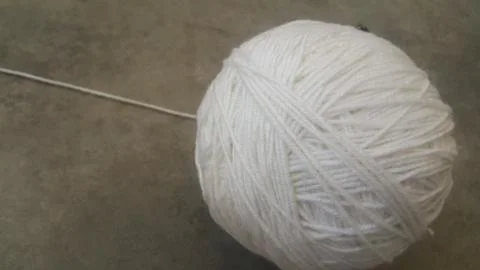 Off white ball of threads wool yarn for knitting on grey floor background Stock Photos