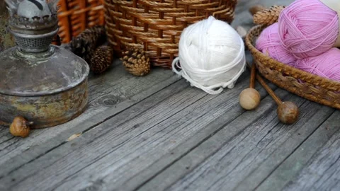 White ball of wool threads roll to basket with pink balls on vintage wood desk Stock Footage 118254974