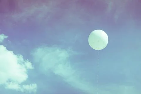 White balloons floating in the sky with clouds. Stock Photos