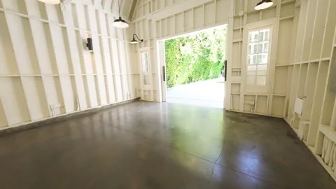 White barn event space opening onto a green backyard lawn Stock Footage 345703099