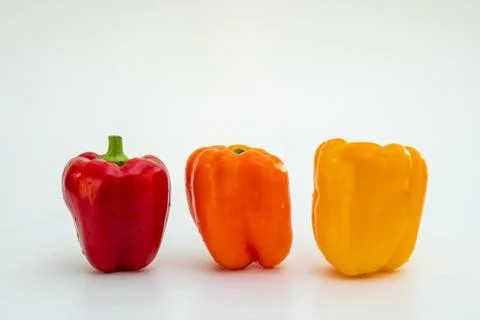 On a white base three peppers of different colours Stock Photos