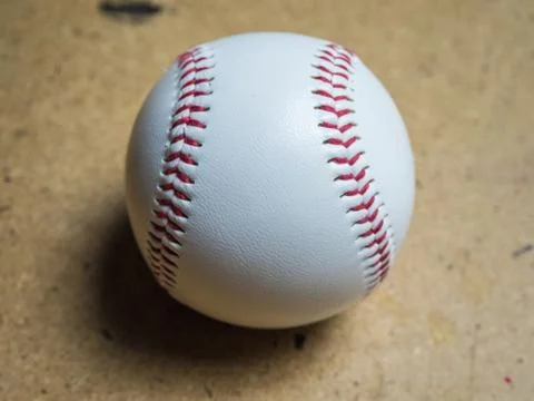 White baseball ball with red threads on a wooden surface Stock Photos