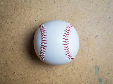 White baseball ball with red threads on a wooden surface Stock Photos