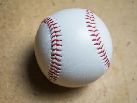 White baseball ball with red threads on a wooden surface Stock Photos