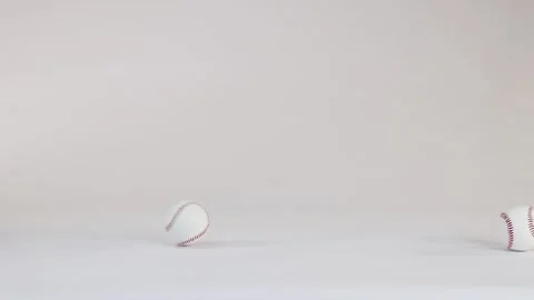 White Baseball with Red Stitching Bouncing Across a Plain White Background Stock Footage 328208335