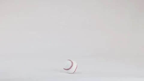 White Baseball with Red Stitching Bouncing on a Plain White Background Stock Footage 328498848