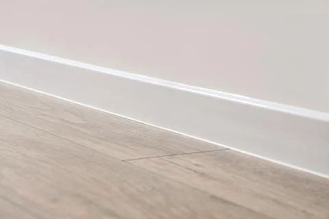 White baseboard trim and light wood laminate flooring in a modern home interi Stock Photos