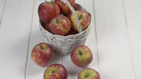 White basket with red apples on table white wood.Tilt movement and top view Stock Footage 72117218