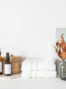 White bath background front view with glass vase, cosmetics, white towels and Stock Photos