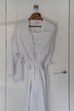 White bathrobe hanging on rack Stock Photos