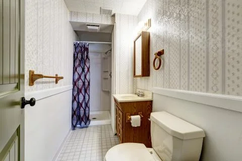 White bathroom interior with tile floor, wooden cabinets, shower and white si Stock Photos