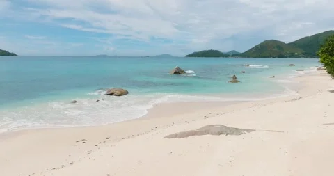 White beach with turquoise waters and scattered rocks. Praslin, Seychelles. Stock Footage 302698906