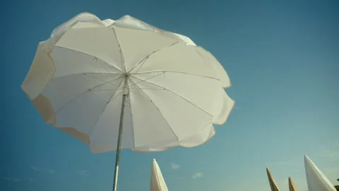 White beach umbrella providing shade on a sunny day. Symbolizing summer Stock Footage 343221925