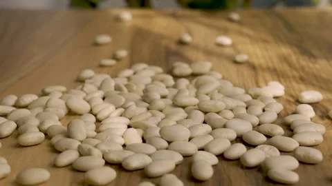 White beans falling on wooden table 4k 10bit slow motion Stockbeeldmateriaal 332571451