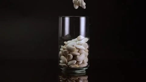 White beans spilling into a glass container in slow motion, set against a b.. Stock Footage 263217426
