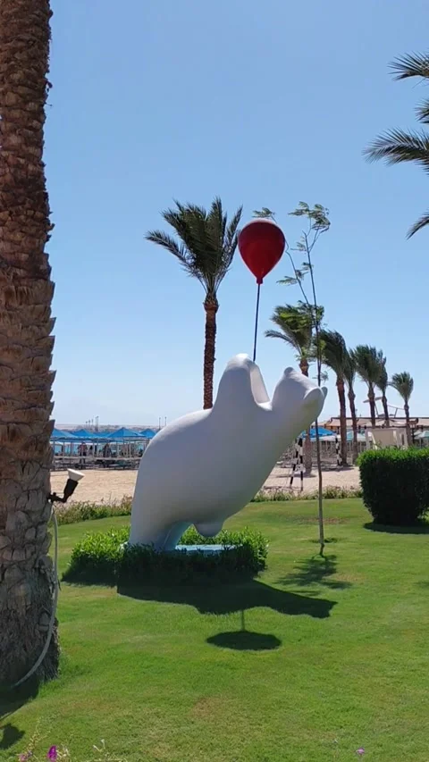 White bear sculpture with red balloon on green lawn in Sahl Hasheesh Egypt Stock Footage 337606616