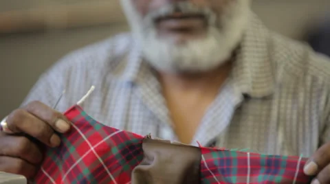 White beard's man sewing with scissors in a dressmaker's factory (close up sh Stock Footage 31360542