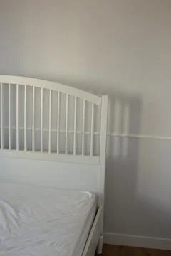 White bed in an empty bright room Stock Photos