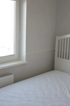 White bed in an empty bright room Stock Photos